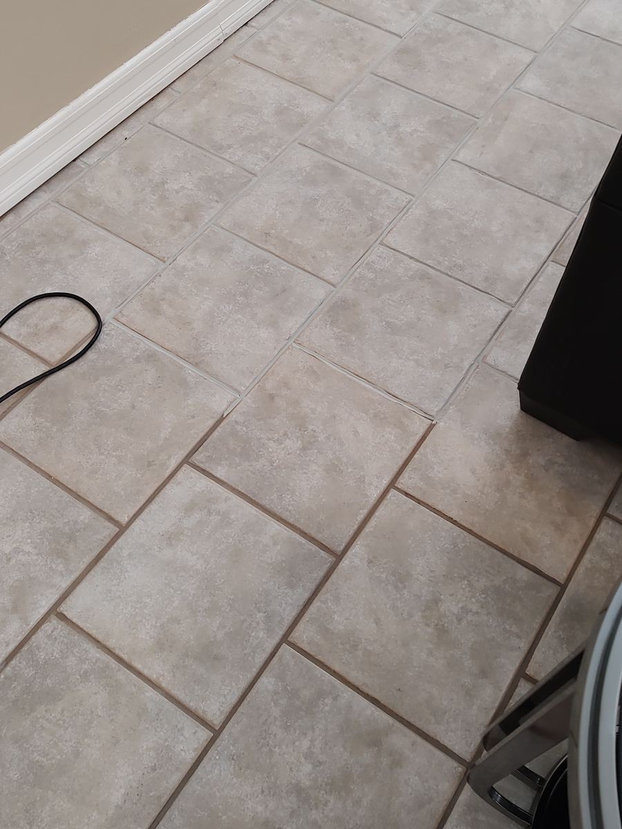 Tile floor with recolored light grout in the upper half and original dark grout in the lower half