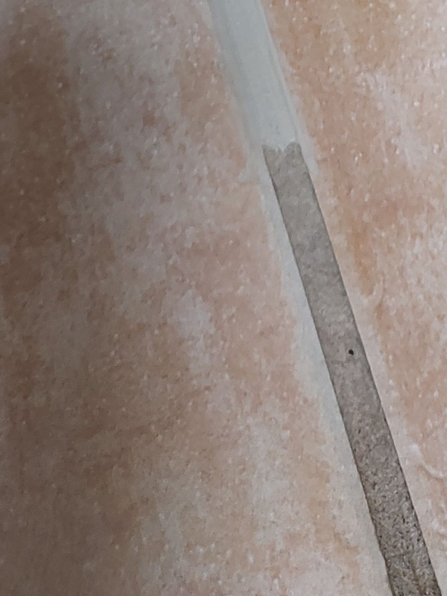 Close-up of a terracotta grout line: recolored light grout at the top meets the original dark grout below